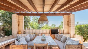 Une terrasse extérieure avec une table en bois, des bancs et un barbecue.