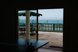 A view from inside a room to an outdoor patio with a pool, a table, and chairs. - Holiday Home 'Casa Das Camarinhas' with Sea View, Private Pool and Wi-Fi (Murtinheira)