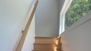 A wooden staircase with a handrail, leading to a landing with a window overlooking greenery. - Fantastic views, comfortable beds. Close to Banya Bathhouse Spa & Crystal Castle (Mullumbimby)