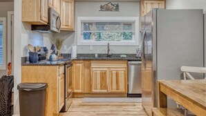 A kitchen with wooden cabinets, a stainless steel refrigerator, and a window with blinds. - Vintage Charm at Mt Air Base of Hood - Unit 4 (Welches)