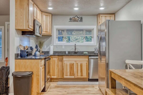 A kitchen with wooden cabinets, a stainless steel refrigerator, and a window with blinds. - Vintage Charm at Mt Air Base of Hood - Unit 4 (Welches)