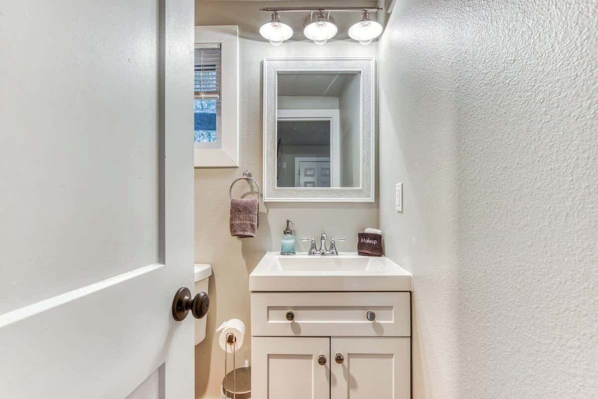 Baño con lavamanos blanco, espejo y toallero.