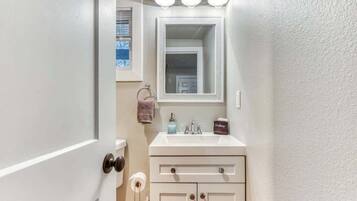 Baño con lavamanos blanco, espejo y toallero.
