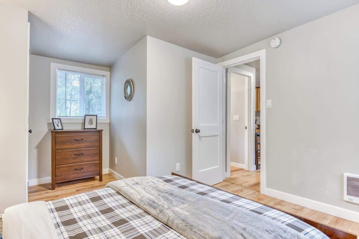 Quarto com cama, penteadeira, janela e porta que dá para outro cômodo.