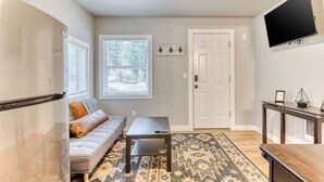 Un salon moderne avec un canapé, une table basse, un tapis à motifs, une porte et un téléviseur fixé au mur.