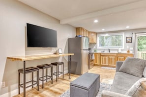 A modern kitchen with a flat-screen TV, wooden cabinets, and a built-in refrigerator.