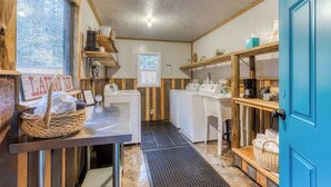 Une buanderie avec des murs en bois, un lave-linge, un sèche-linge et des étagères remplies de produits de lessive.