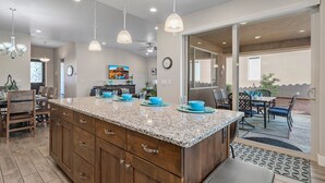 A spacious kitchen with a granite countertop, wooden cabinets, and pendant lighting.