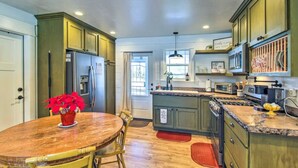 A kitchen with wooden cabinets, a central island, a dining table with chairs, and a refrigerator.