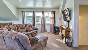 A cozy living room with a sectional sofa, a fireplace, and a television mounted on the wall.