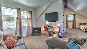 A cozy living room with a fireplace, a flat-screen TV mounted on the wall, and a comfortable seating area with sofas.