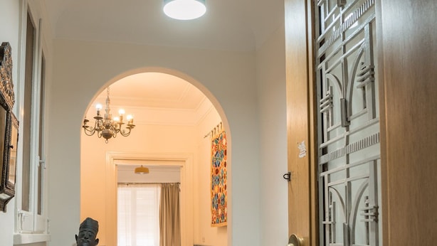 A hallway leading to a living room with a sofa, a rug, and a statue.