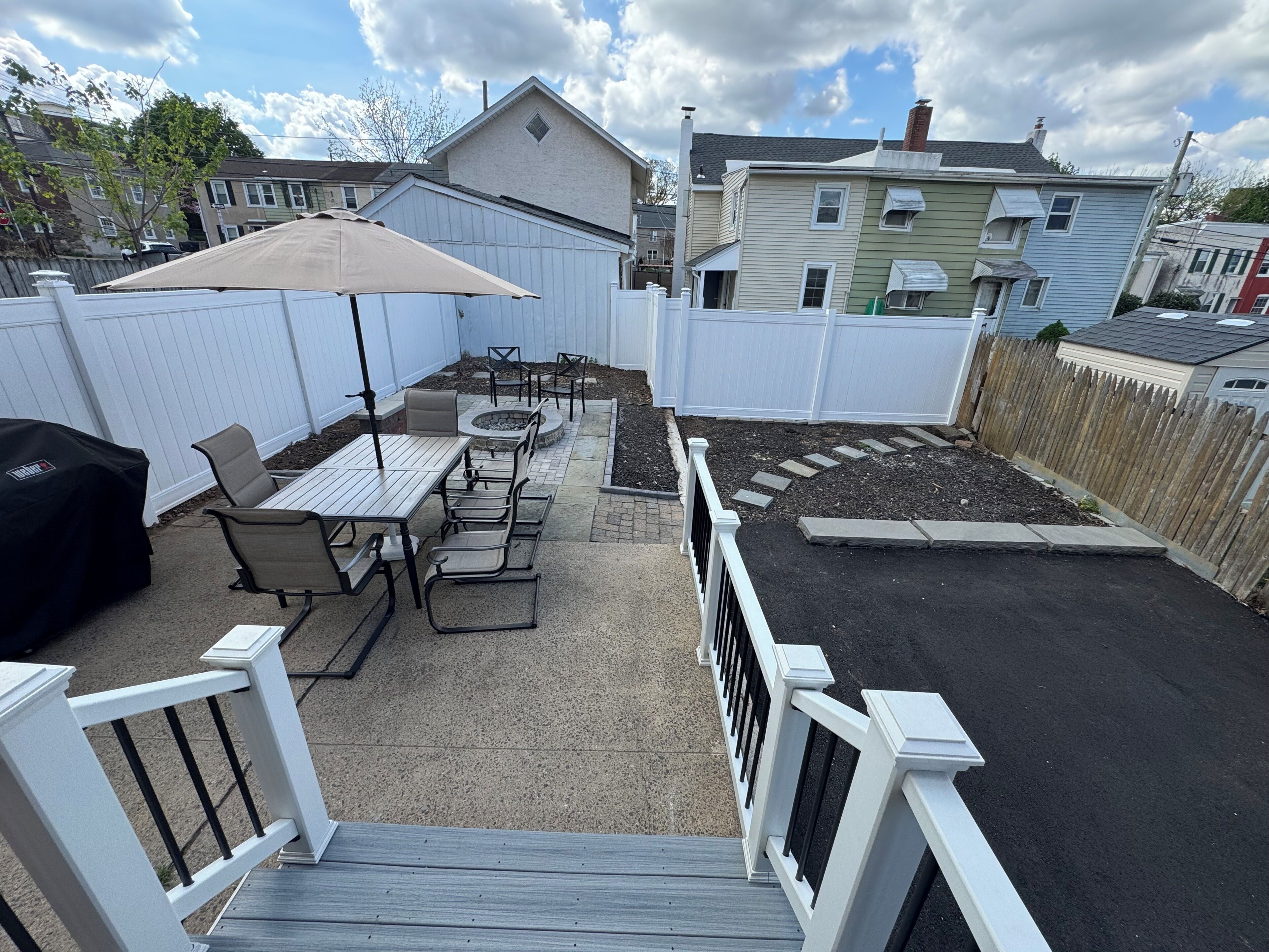 Une terrasse à l’arrière de la maison, avec une table et des chaises, un barbecue et un foyer extérieur.