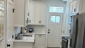 A modern kitchen with white cabinetry, a stainless steel refrigerator, and a built-in oven.
