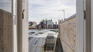 Une vue depuis une fenêtre donnant sur un toit avec plusieurs toits plats et une cheminée.