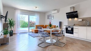 A modern apartment with a dining area, kitchen, and a sliding glass door leading to a balcony. - Vacation home Eja by Interhome (Buje/Plovanija)
