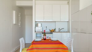 Une cuisine de taille réduite avec des meubles blancs, un four à micro-ondes et un évier.
