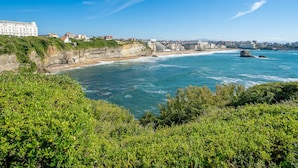 Un paysage urbain côtier avec une falaise imposante, une plage et un grand bâtiment d’hôtel.