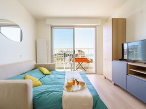 Relax in a spacious room with a large bed, flat-screen TV, and a balcony offering a city view.