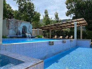 Relax by the pool surrounded by lush greenery and a tranquil atmosphere.