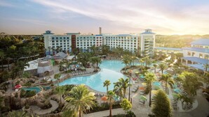 Un complexe hôtelier doté de plusieurs piscines, de palmiers et d’un grand bâtiment surmonté d’un toit bleu.