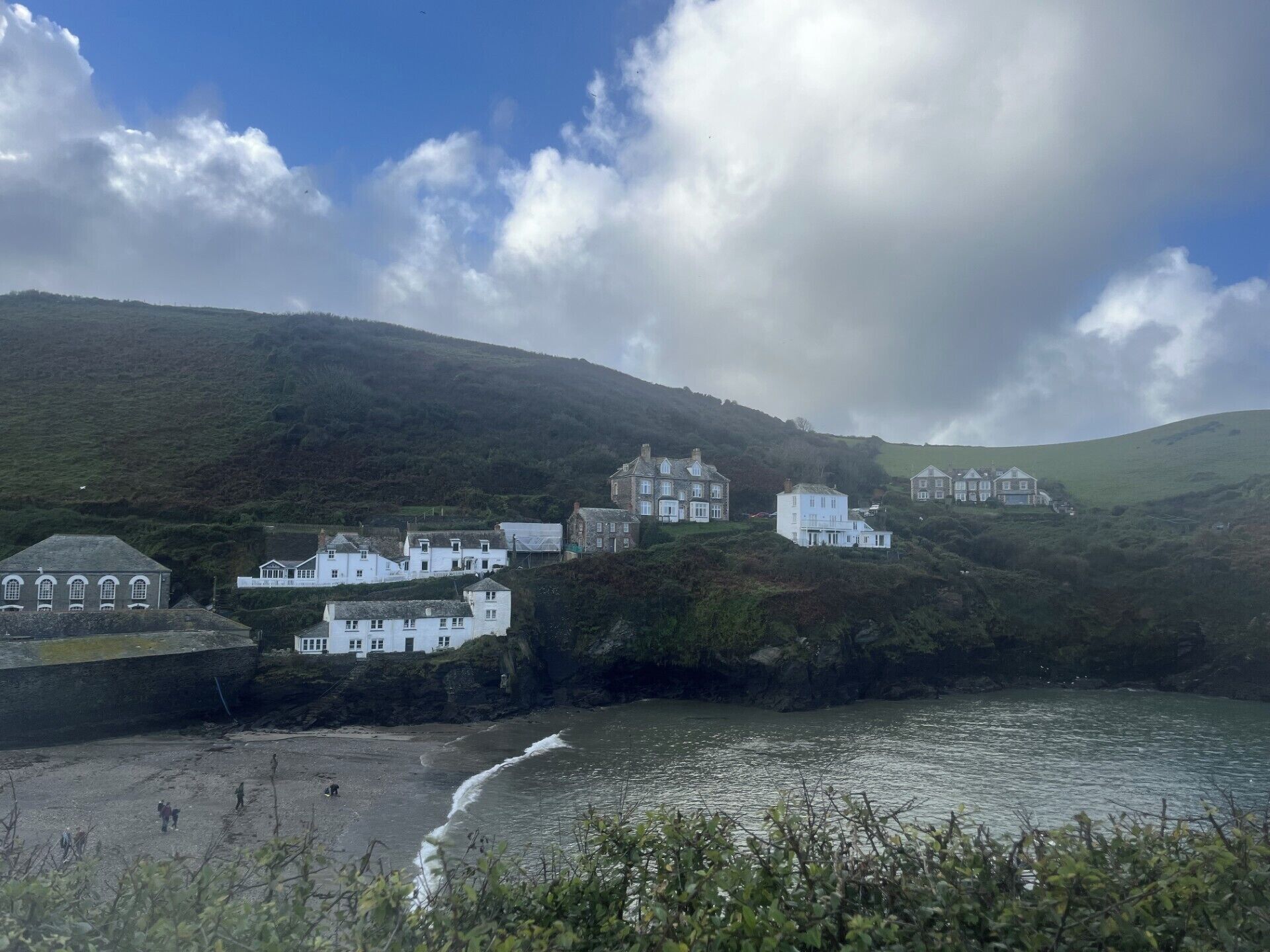 A coastal area with white buildings, a beach, and a hilly backdrop.