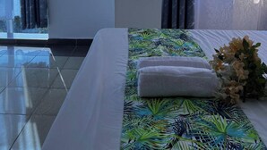 Quarto de hotel com cama, uma janela grande e piso de azulejos.