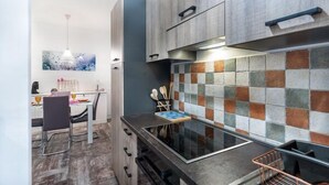 A modern kitchen with a black countertop, a built-in stove, and a backsplash with multicolored tiles.