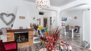 A modern living room with a fireplace, colorful chairs, and a dining area.