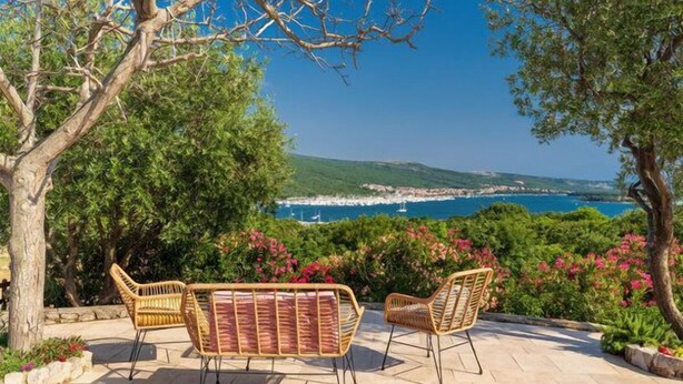 A patio with wicker furniture overlooking a coastal view.