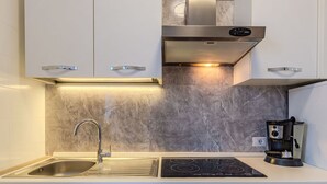 A modern kitchen with a stainless steel sink, an induction cooktop, a built-in oven, and a coffee machine. - Lovely apartment for 4 people with WIFI, TV, balcony and panoramic view (Dorio)