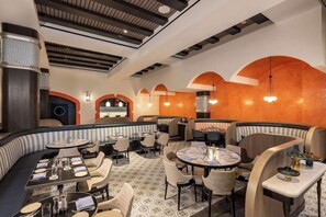 Een restaurant met ronde tafels, zitjes en een vloer met een patroon.