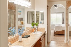 Un bagno con un grande specchio, due lavandini e zona doccia.