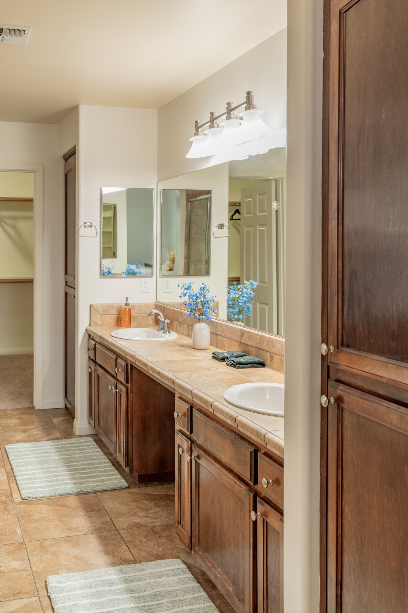 A bathroom with a double sink vanity, a large mirror, and a shower area.
