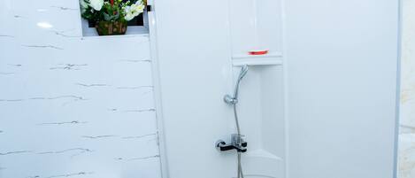 Un baño con inodoro, ducha y ventana con flores.