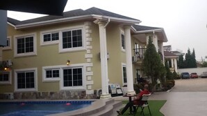 A large house with a swimming pool, a covered patio, and a well-maintained garden. - Fokuzzy Lodge (Madina)