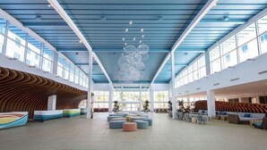 A spacious lobby with a high ceiling, large windows, and a central seating area.