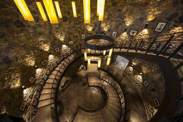 Una escalera de caracol en un interior de paredes de piedra, con varios niveles y barandillas.