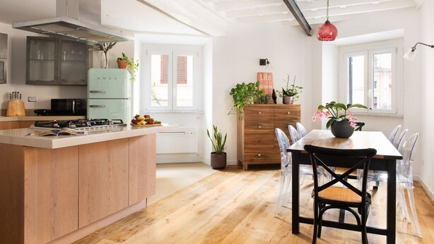 A modern kitchen with a central island, wooden cabinets, and a dining area with a table and chairs.