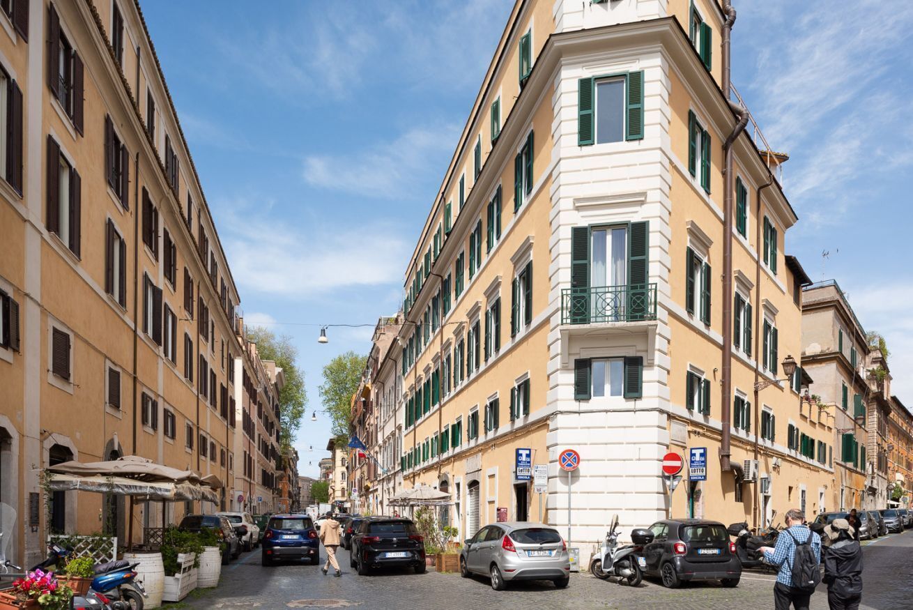 A street with parked cars and buildings with balconies.