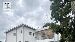 Ein modernes, zweistöckiges Gebäude mit flachem Dach, weißen Außenwänden und einem Balkon im oberen Stockwerk.