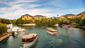 Ein Fluss mit Booten und einem Hotel mit mehreren Gebäuden und Palmen.