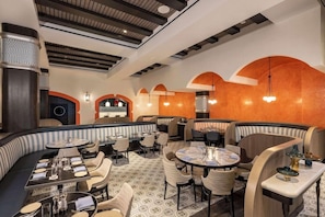 A restaurant with round tables, booths, and a patterned floor.