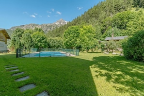 Quintal com piscina, degraus de pedra e montanhas ao fundo.