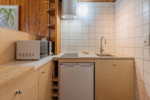Uma cozinha compacta com armários de madeira, micro-ondas, pia e máquina de lavar louça.