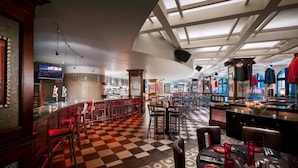 A restaurant with a checkered floor, bar area with red chairs, and a counter with sports jerseys.