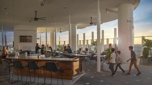 Un espace bar extérieur doté de hauts plafonds, de mobilier moderne et offrant une vue sur la ville.