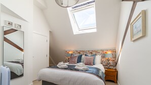 A bedroom with a large bed, a skylight, a mirror, a bedside table, and a nightstand. - Lobster House by Interhome (Newquay)