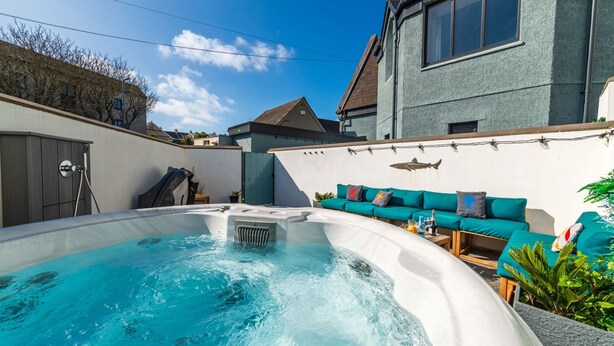 A hot tub in a backyard with a sofa and a wall-mounted shark decoration. - Lobster House by Interhome (Newquay)