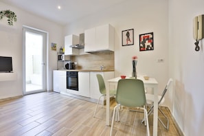 Une cuisine moderne avec des armoires blanches, un four encastré et un coin repas comprenant une table et des chaises.